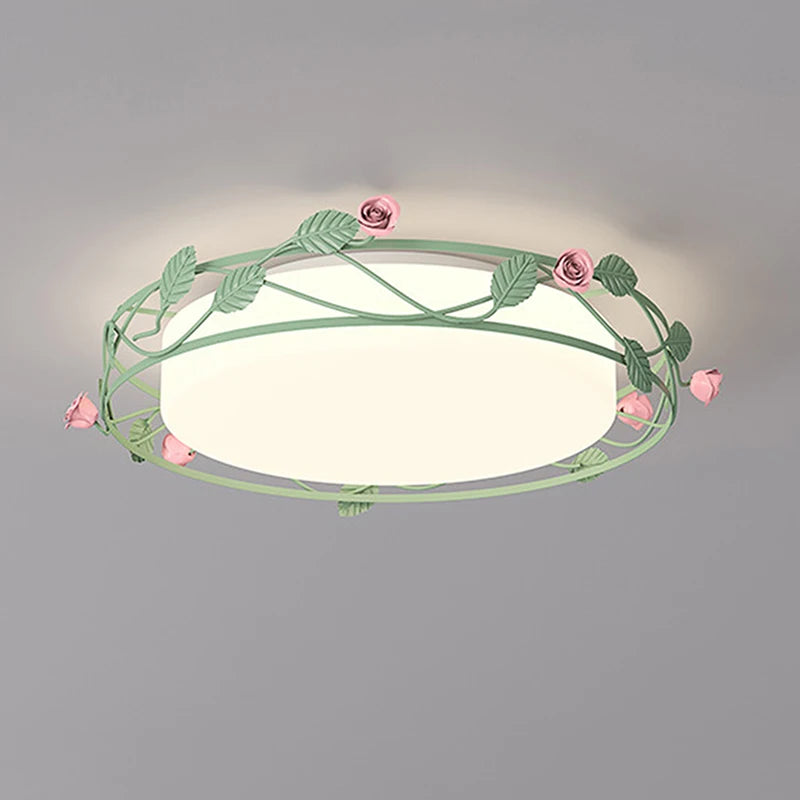 A green metal flush mount ceiling light decorated with pink roses and green leaves, illuminating a room.