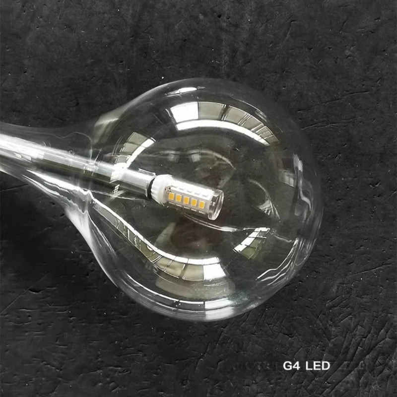 Close-up view inside a clear glass teardrop pendant light showing the G4 LED bulb.
