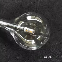 Close-up view inside a clear glass teardrop pendant light showing the G4 LED bulb.