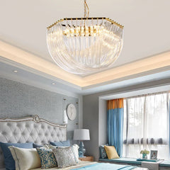 View of a gold crystal waterfall chandelier from below, highlighting its chain suspension and radiant light in a bedroom setting.