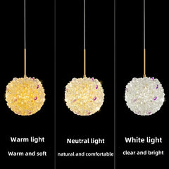 A display showing the same gold crystal orb pendant light illuminated with warm light, neutral light, and white light.