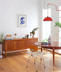 Modern interior with wooden furniture, red pendant light, and abstract art on the wall.