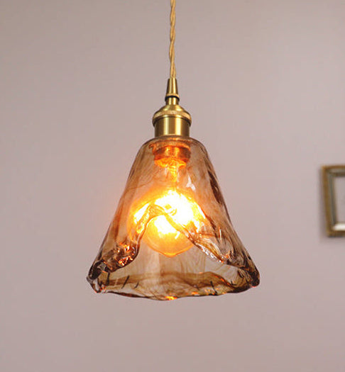 Vintage-style pendant light with a glass shade and gold fixture on a plain background