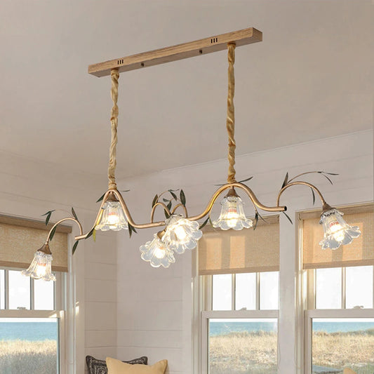 Gold floral pendant light with five glass shades, suspended by braided ropes from a wooden bar.