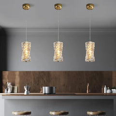 Three pendant lights hanging above a kitchen counter with a neutral color scheme.