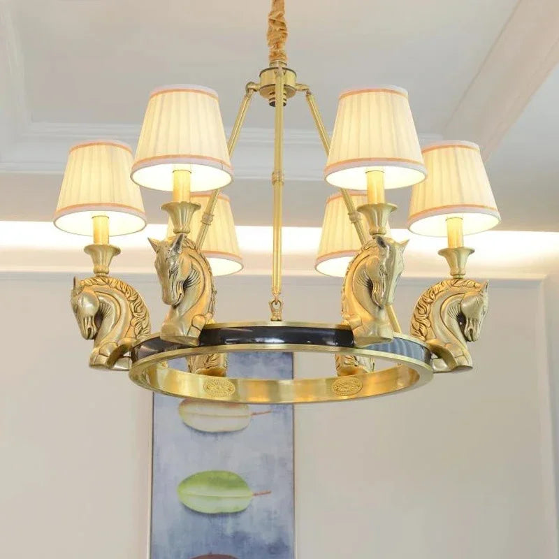 Gold chandelier with horse head designs and white lampshades in a room setting.