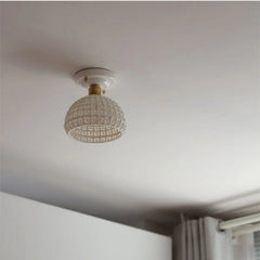 Ceiling light fixture with decorative glass shade on a white ceiling