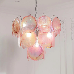 Pink and orange chandelier hanging against a white wall