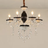 Close-up of a black and crystal candelabra chandelier with five illuminated candle-style bulbs and cascading teardrop crystals.