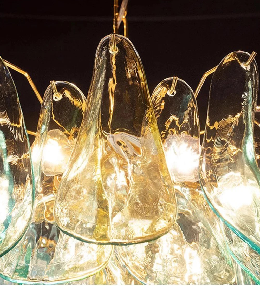 Glass chandelier with teardrop shapes and gold accents against a dark background