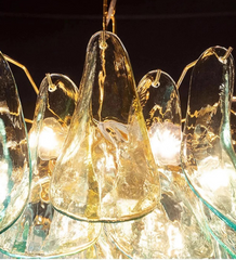 Glass chandelier with teardrop shapes and gold accents against a dark background