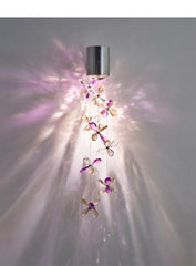 Side view of a polished chrome wall sconce with crystal flower accents, highlighting the light refraction and shadow effects on the wall.