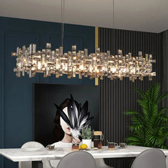 Rectangular polished chrome crystal chandelier installed in a dining room setting above a marble table.