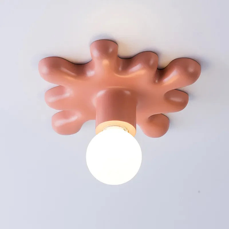 Close-up of a pink ceramic starburst wall sconce, showing its textured surface and the light bulb socket.