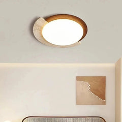 Close-up of an oval flush mount ceiling light with a textured natural stone accent and a warm LED glow against a white ceiling.