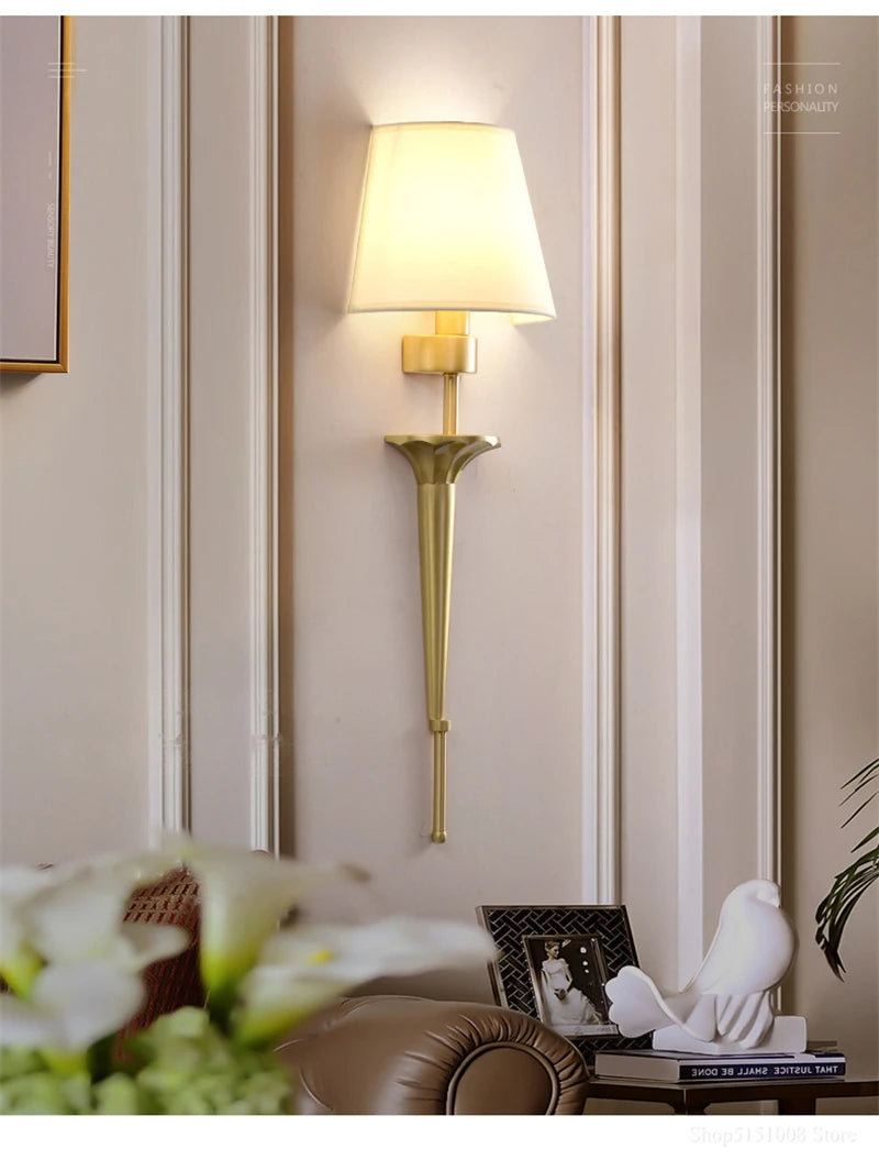 Gold wall sconce on a wall with decorative elements in the foreground