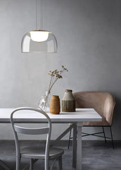 Modern dining area with a white table, gray chairs, and a pendant light.