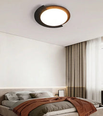 Ceiling light fixture in a bedroom setting with a bed and curtains.