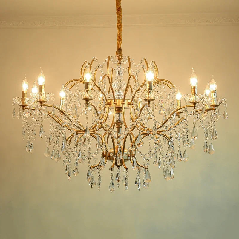 Close-up of a gold chandelier showcasing intricate crystal droplets and polished metal arms, lit by warm bulbs.