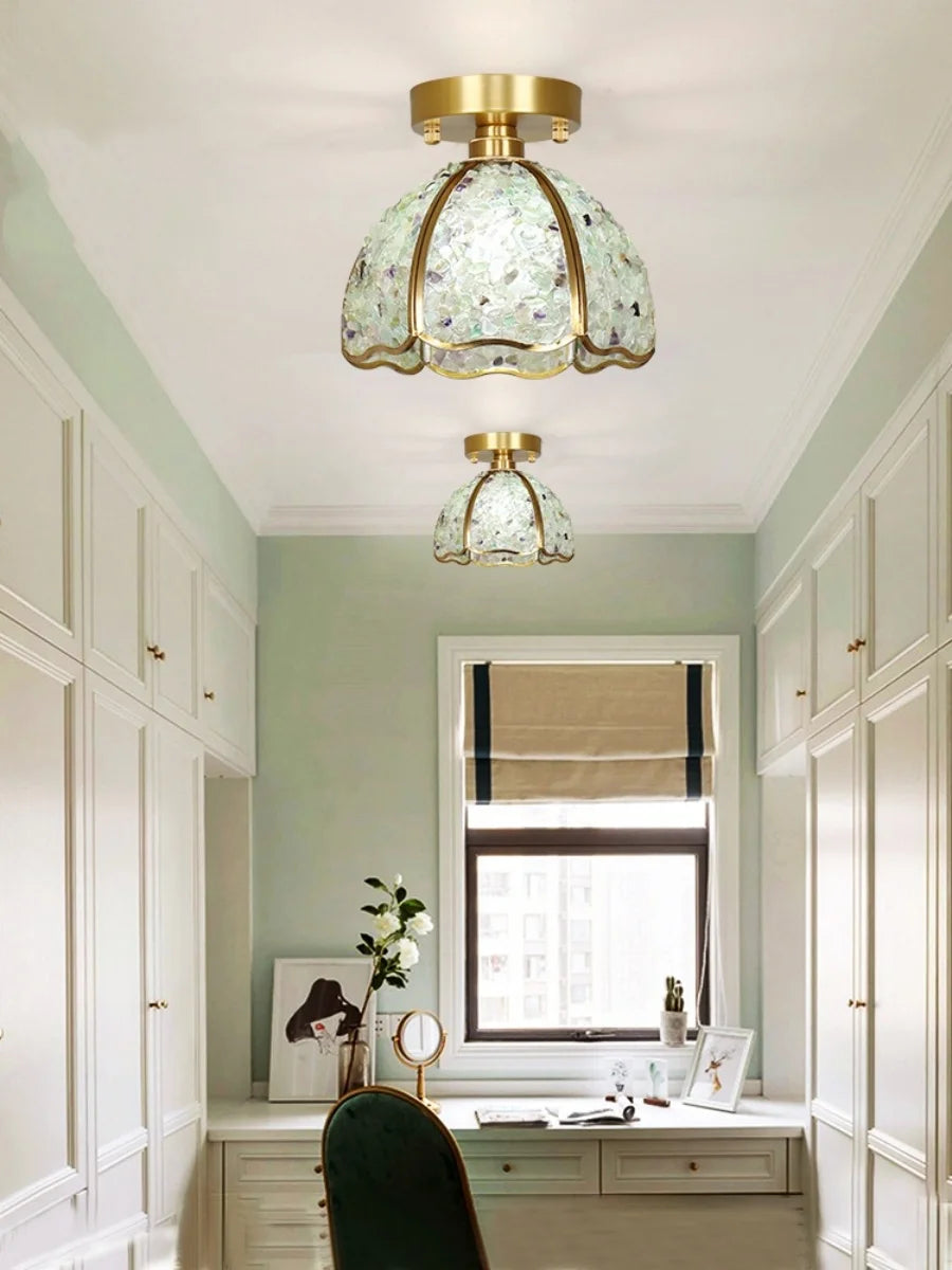 Ceiling lights with green glass shades in a room with white walls and a window.