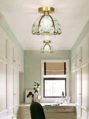 Ceiling lights with green glass shades in a room with white walls and a window.