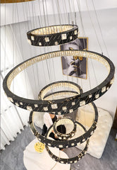 Decorative chandelier with multiple rings and crystals in a room setting.