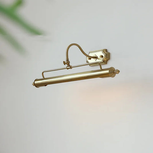 A gold-colored linear wall sconce with an adjustable arm and shade is mounted on a white wall.
