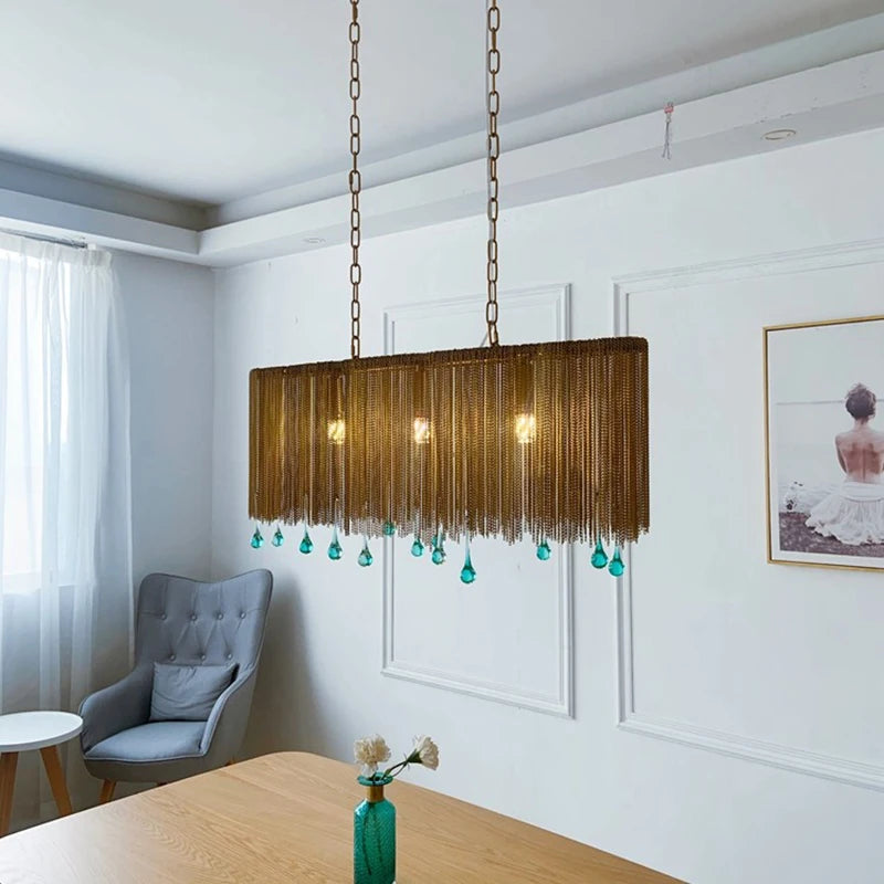 Gold chain chandelier with blue teardrop crystals in a room with a grey armchair