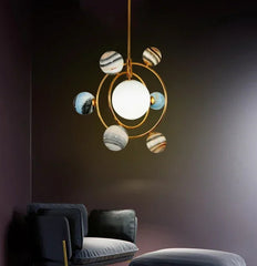 Modern pendant light with marble-like design hanging in a room with dark walls and gray furniture.