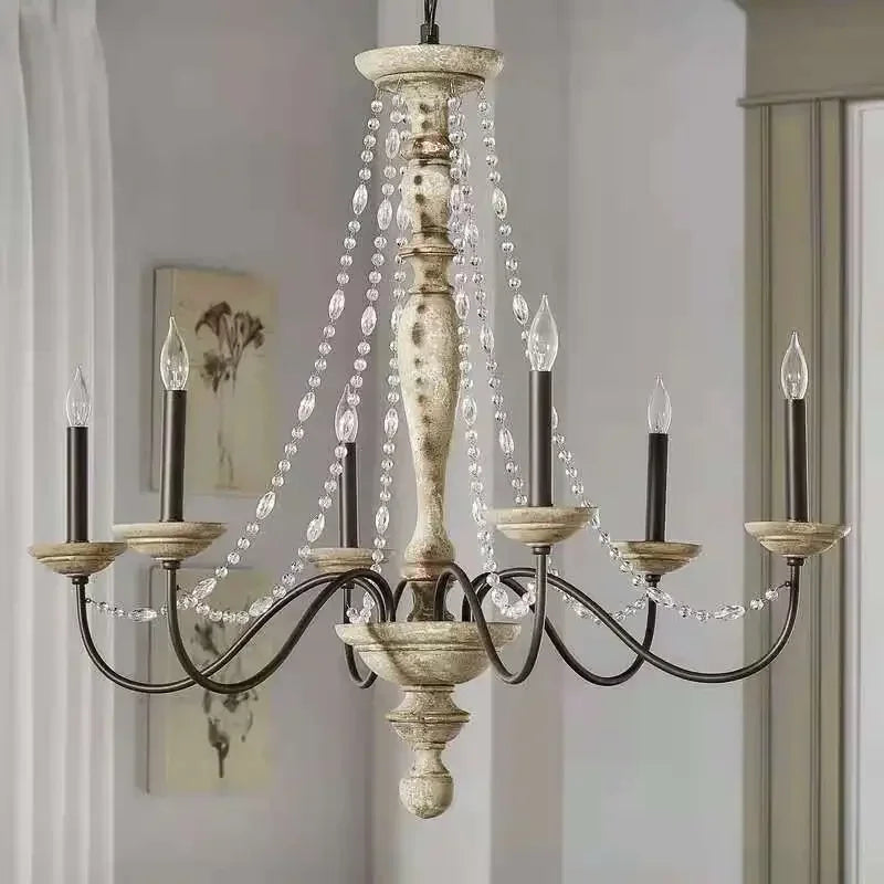 A detailed shot of the distressed wood central column and candle-style lights of a crystal chandelier.