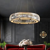 Circular chrome pendant light with clear crystals, suspended from the ceiling in a dimly lit room.