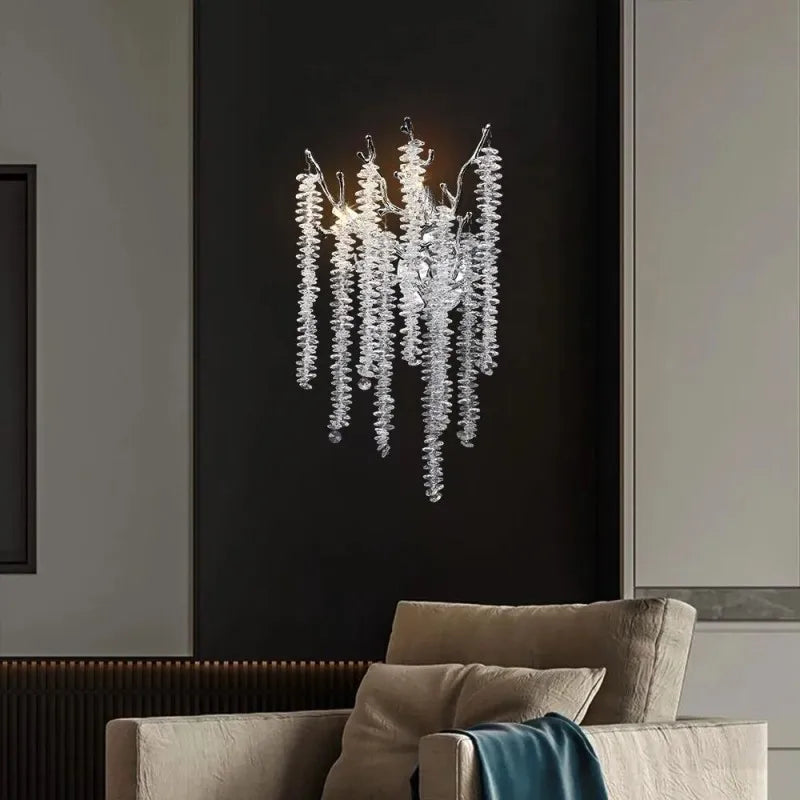 A single gold crystal branch wall sconce mounted on a dark wall above a chair, showcasing its intricate design.