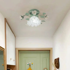 A green floral flush mount ceiling light installed on a ceiling above a green door in a hallway, with white cabinets visible.