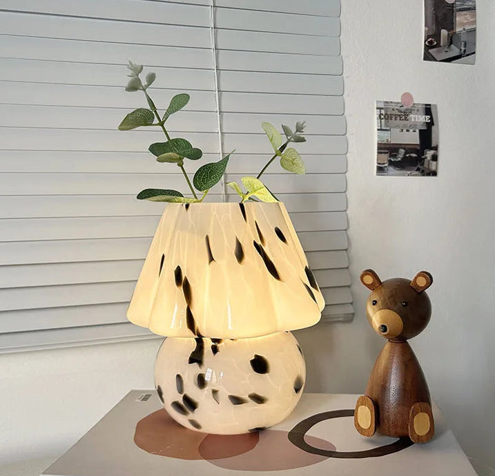 Decorative lamp with a plant and wooden bear on a book.