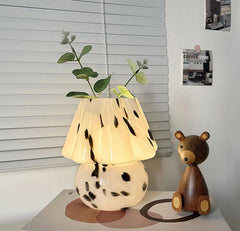 Decorative lamp with a plant and wooden bear on a book.
