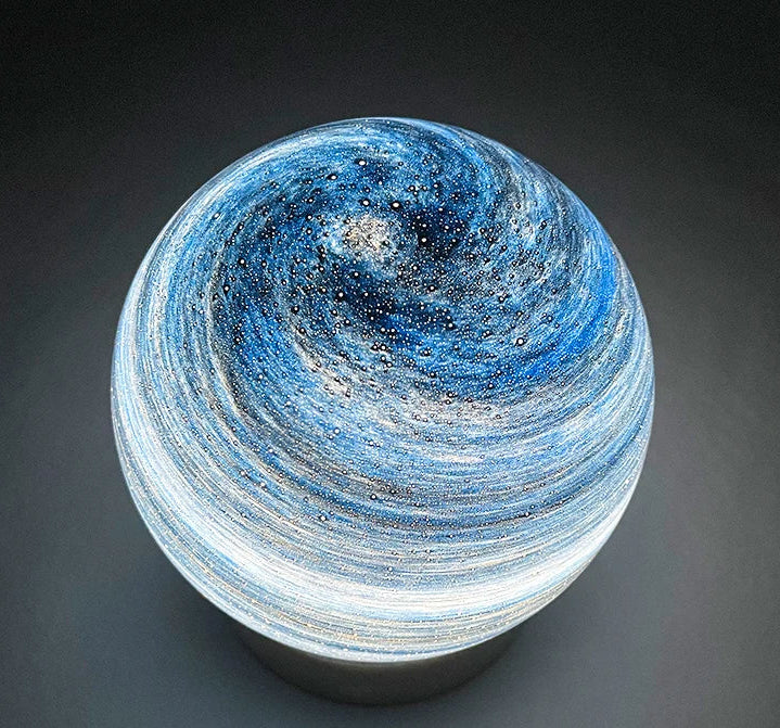Decorative lamp with swirling blue and white design on a dark background