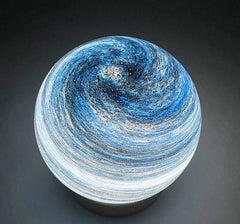 Decorative lamp with swirling blue and white design on a dark background