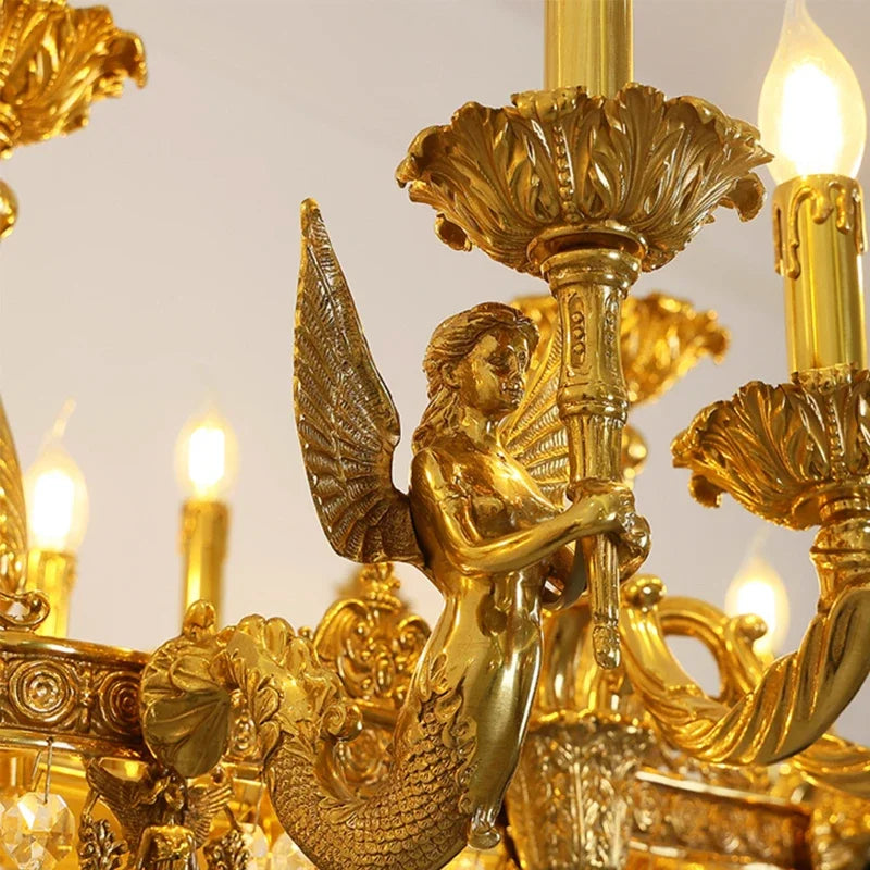 Close-up of the gold chandelier showing a detailed mermaid figure with wings holding a central stem.