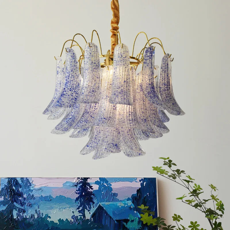 Gold chandelier with cascading bell-shaped glass elements speckled with blue and white, hanging from a rope.