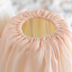 Close-up of a pink pleated fabric item with a blurred background