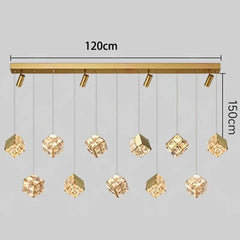 Gold pendant light fixture with hanging crystal cubes on a gray background