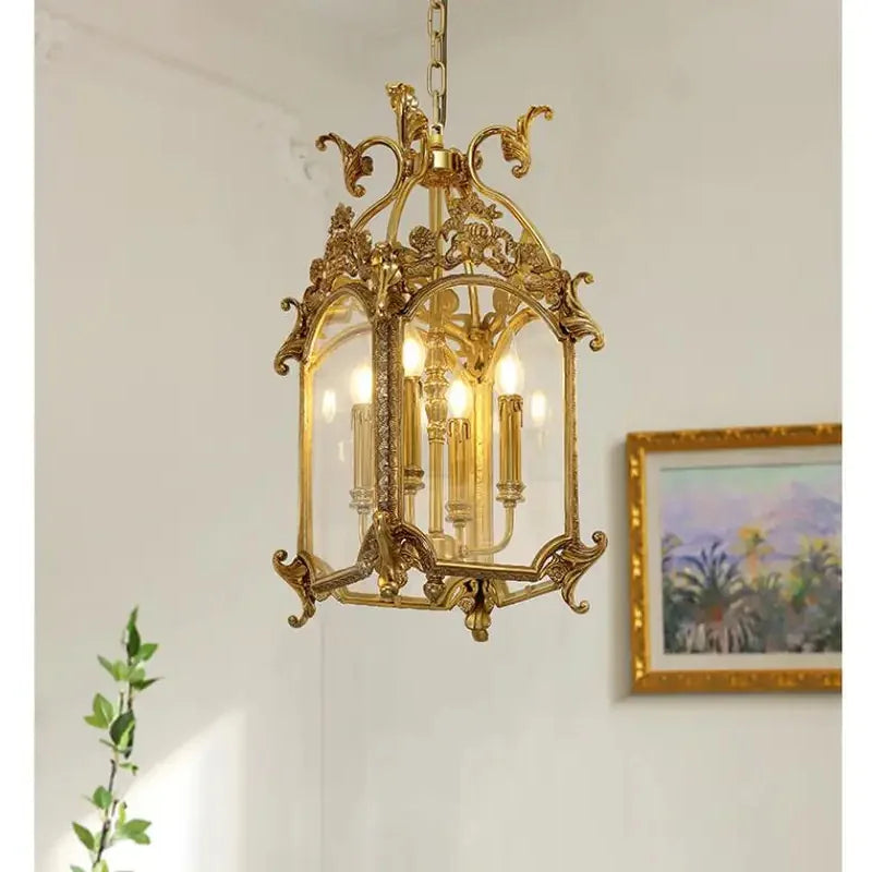 Close-up of the top section of a gold candelabra cage pendant light, highlighting the decorative scrollwork and chain.