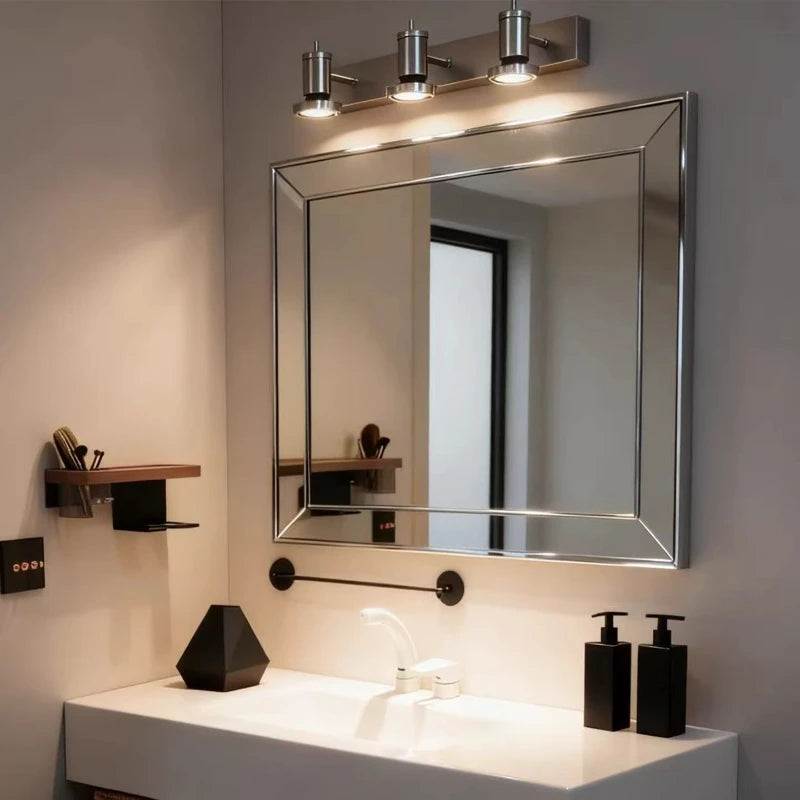 A bathroom vanity area featuring a silver wall sconce with three adjustable LED heads mounted above a large mirror.
