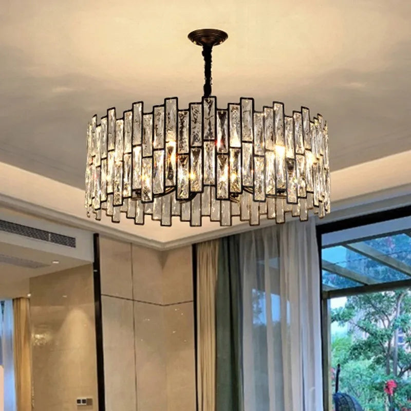 A bright chandelier with clear crystal elements arranged vertically around a black frame, installed in a well-lit room.