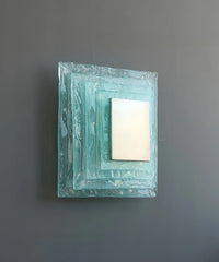 Square wall mirror with decorative frame on a gray wall