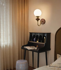 Room interior with a wall sconce, desk, and bed, evoking an antique atmosphere.