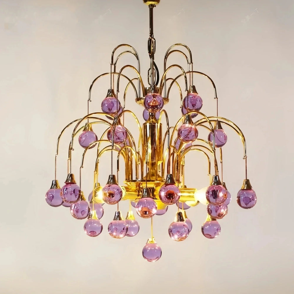 Gold chandelier with cascading purple teardrop glass pendants against a white background