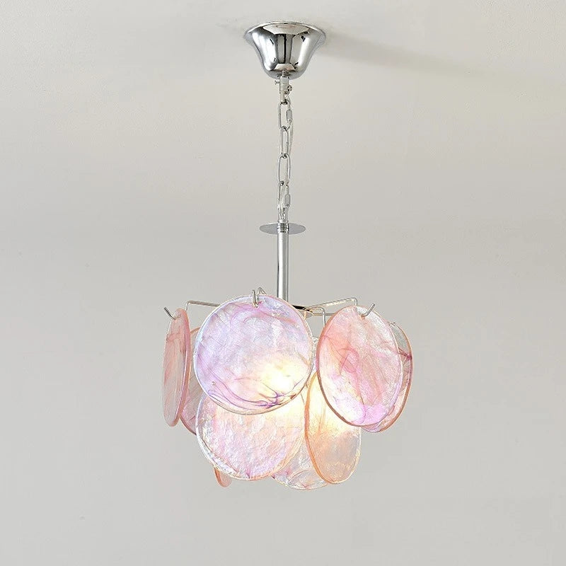 A pink glass disc pendant light with a polished chrome chain and ceiling mount, illuminated from within.