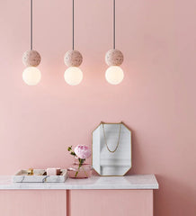 Pink wall with pendant lights, mirror, and decorative items on a white surface.