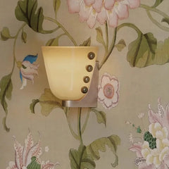 Wall sconce with floral wallpaper in the background